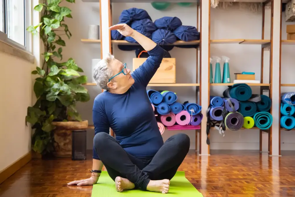 Femme âgée faisant des exercices assise sur un tapis