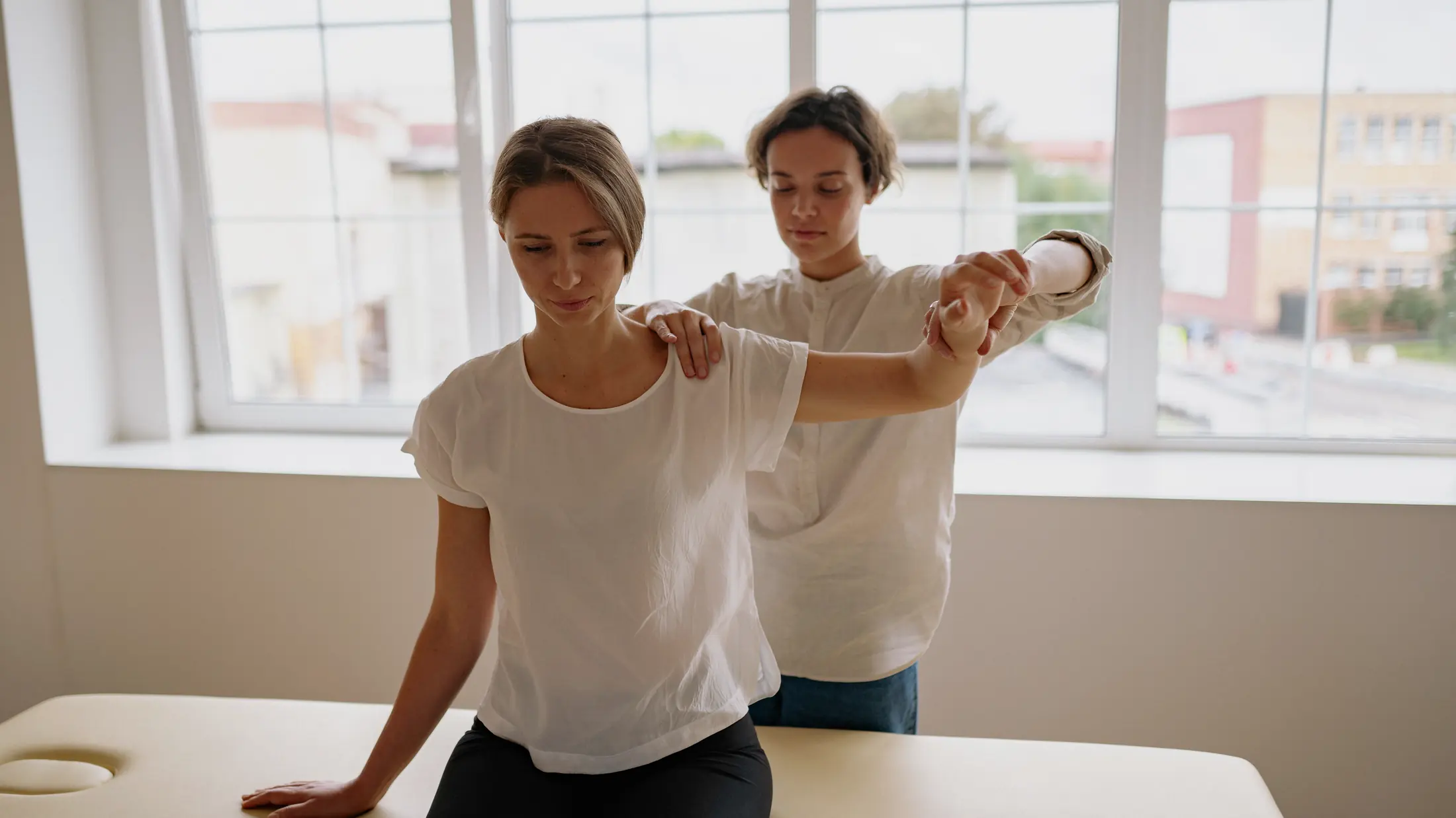 Professionnelle guidant un mouvement d'épaule lors d'une séance