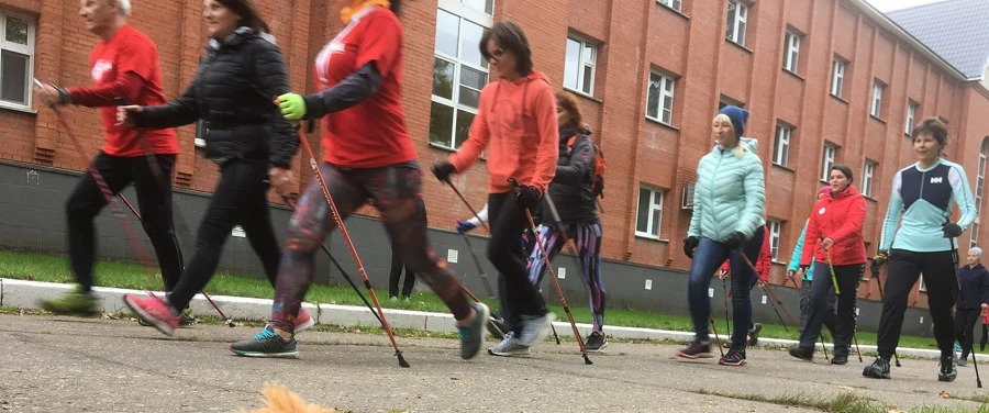 Groupe de marcheurs nordiques avec bâtons sur un trottoir en ville